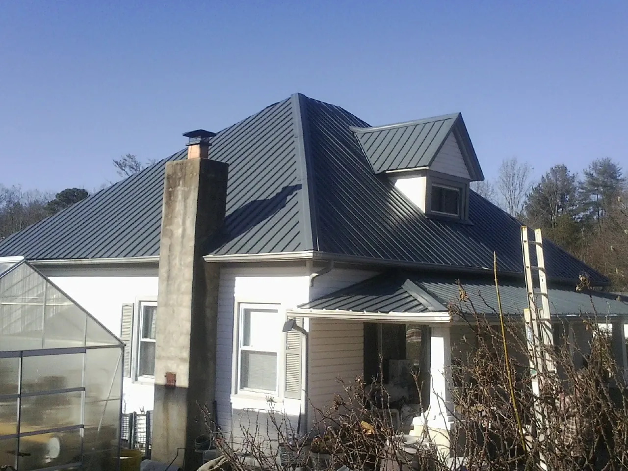 Dark blue standing seam metal roof on a white farmhouse with dormer — Slate & Tile Roof Repair by Roofing Brothers in Brockway