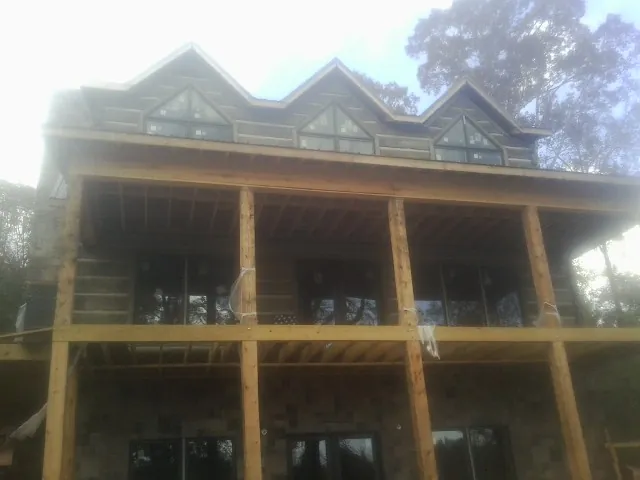 Dormers and porch framing on a large log home under construction — Roof Coating work by our crew in Brockway