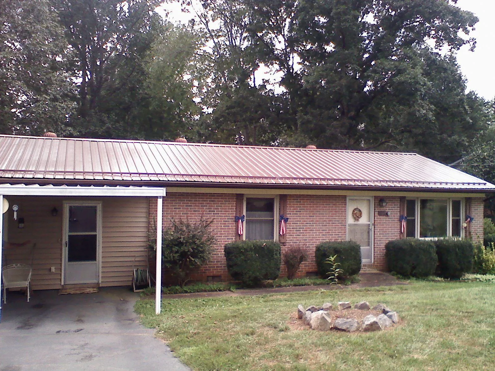 Bronze metal roof and carport on a brick ranch home — Roof Repair work by our crew in Brockway