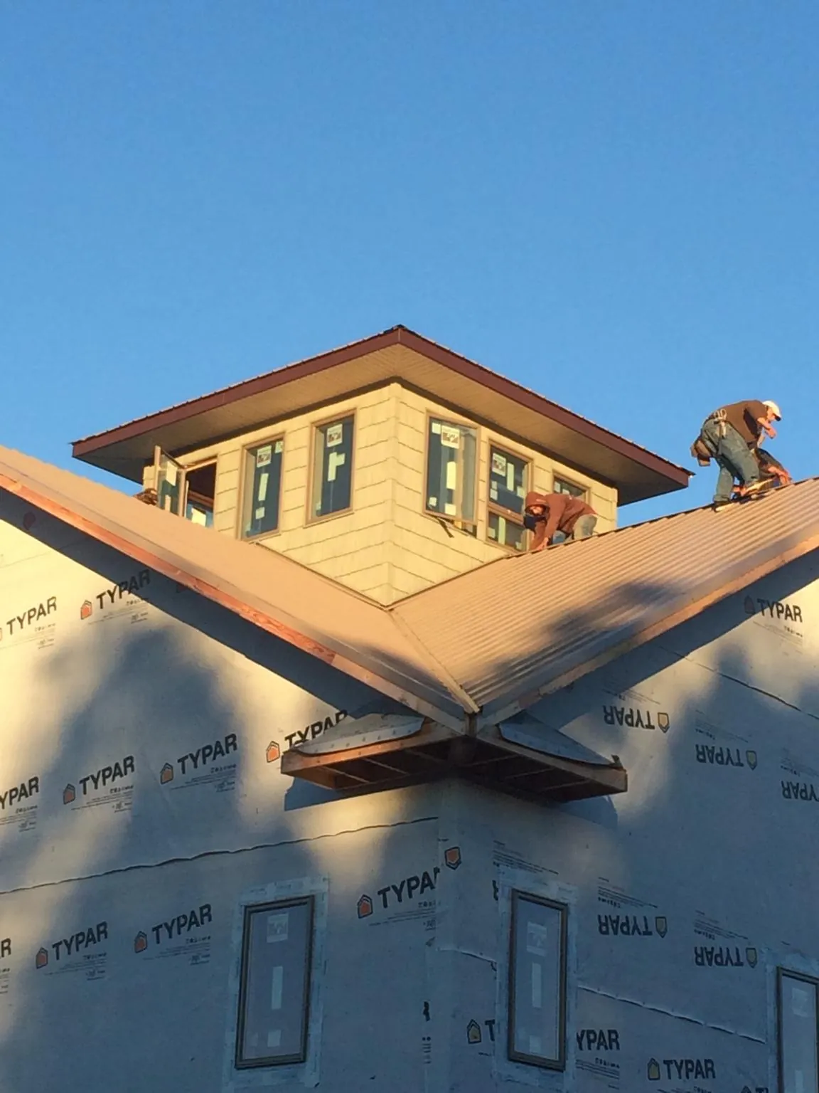 Roofers working around a rooftop cupola on a new metal roof at sunset — Roof Waterproofing in Brockway by Roofing Brothers